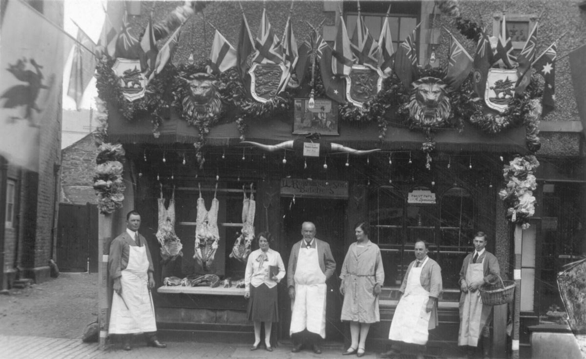 Outside Llewelyn Rowlands butchers on Bridge Street. Llewelyn Rowlands is between the two women in the centre. The other two men in the photo are his staff.
